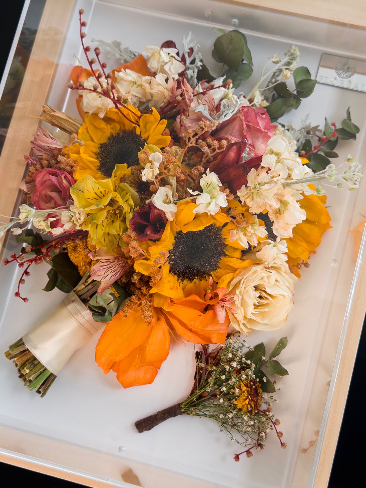 Detalhe de girassóis, rosas e folhagens preservados, mostrando o volume das flores
